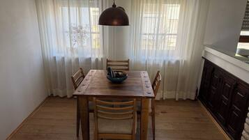 A dining area with a wooden table, chairs, a blue bowl, and a pendant light.