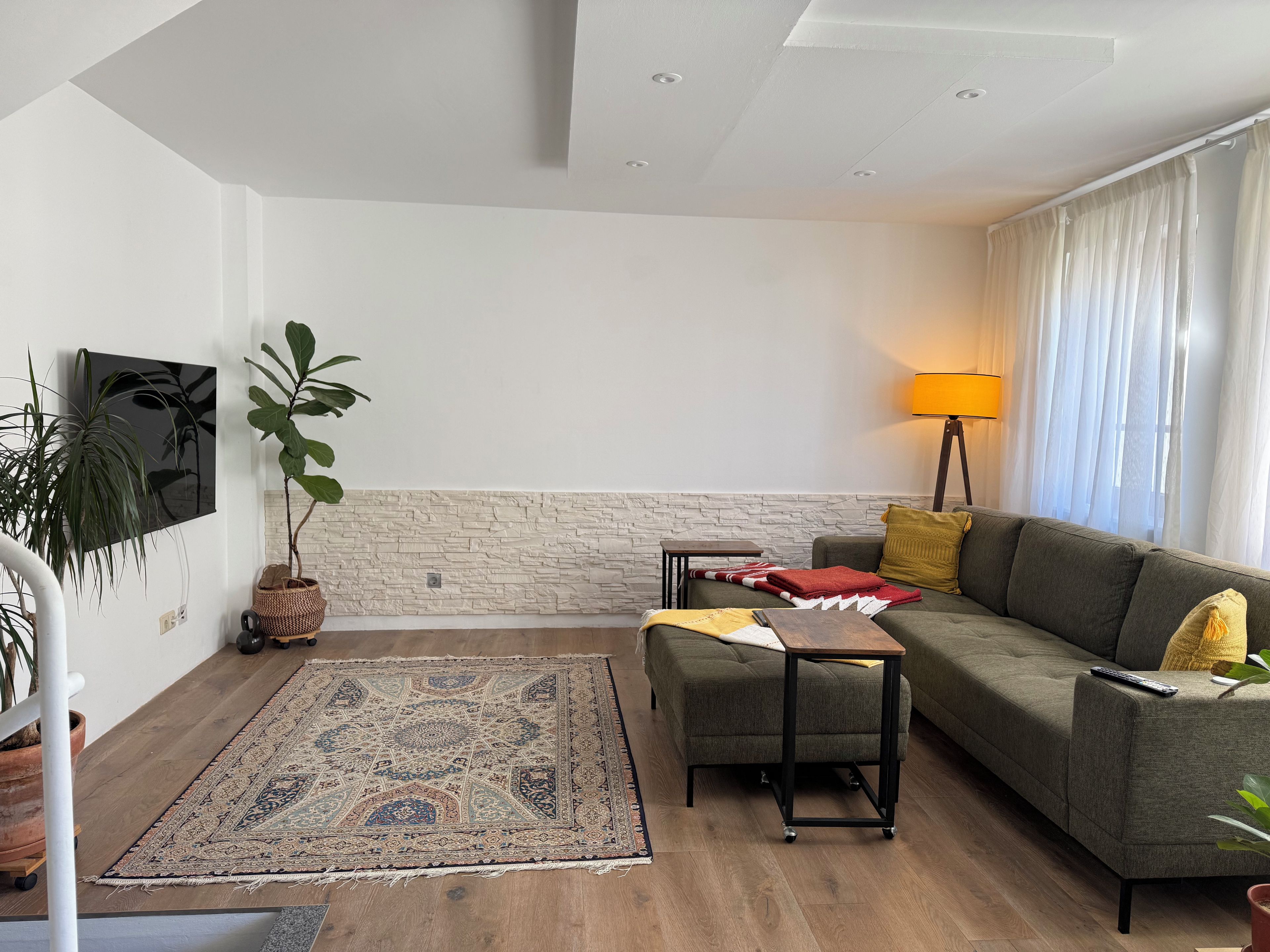 A modern living room with a grey sofa, a small table, a floor lamp, and a large rug.