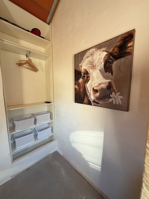 Una habitación con un armario blanco que contiene ropa colgada y toallas dobladas.