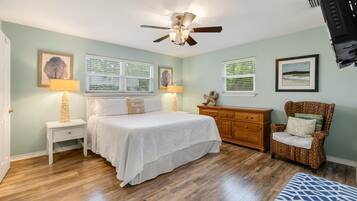 A bedroom with a bed, bedside tables, a dresser, a chair, and a ceiling fan.