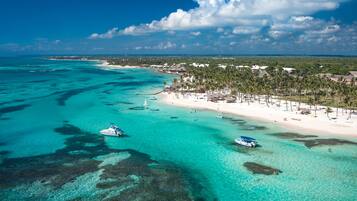 Un complejo turístico frente al mar con aguas turquesas cristalinas, playas de arena y densas palmeras.
