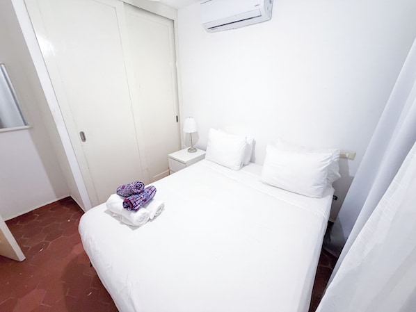 A hotel room with a bed, a nightstand, a lamp, and a folded towel on the bed. - VILLAS and APARTMENTS playa LOS CORALES (Punta Cana)