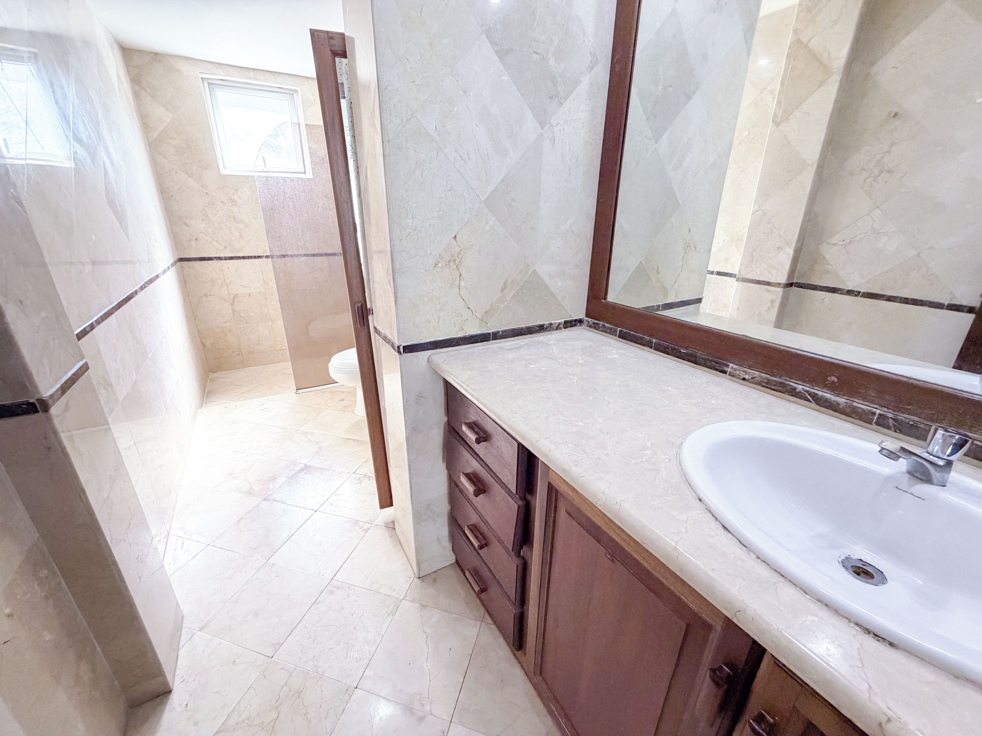 A bathroom with a sink, mirror, and wooden cabinet.