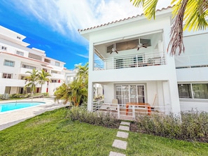 A two-story building with a balcony, a pool, and a well-maintained lawn. - VILLAS and APARTMENTS playa LOS CORALES (Punta Cana)