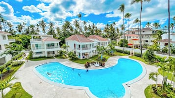 A resort with a large pool, multiple buildings, and palm trees.