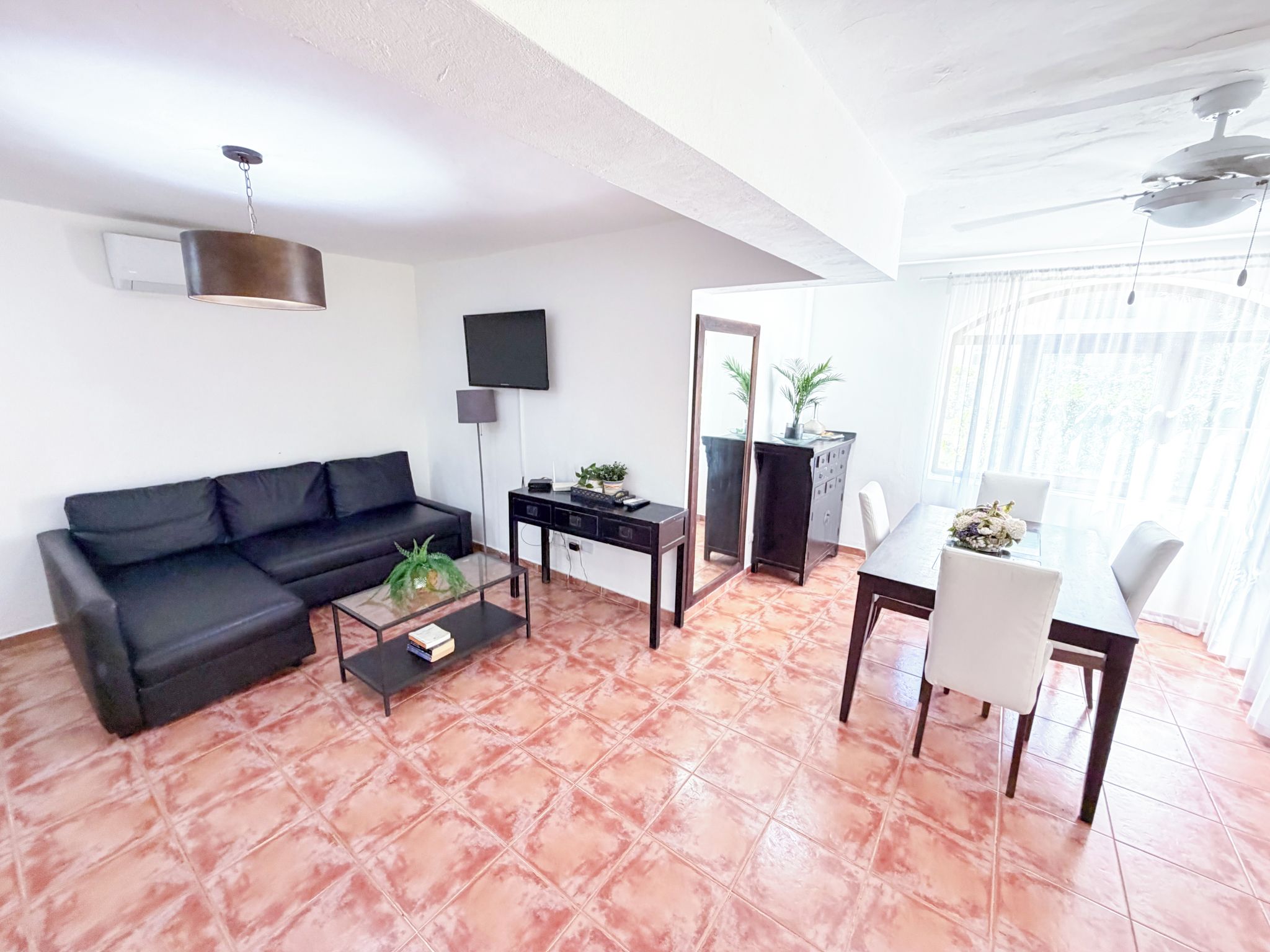 A living room with a sofa, coffee table, TV, and a dining area with a table and chairs.