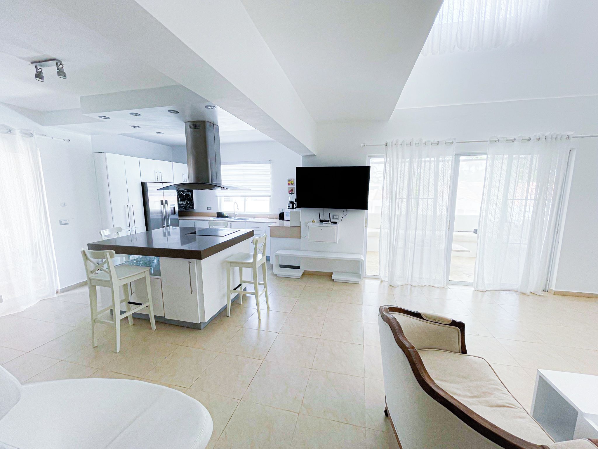 A modern kitchen with a central island, white cabinetry, and a built-in stove.