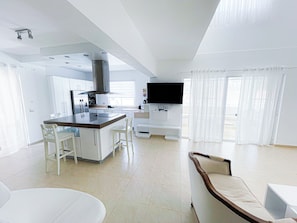 A modern kitchen with a central island, white cabinetry, and a built-in stove.
