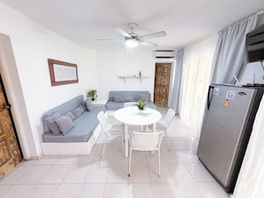 A compact living space with a dining area, a kitchenette, and a seating area with a ceiling fan. - VILLAS and APARTMENTS playa LOS CORALES (Punta Cana)