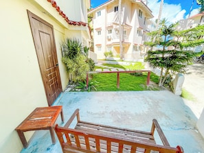 A courtyard with a wooden bench, a door, and a small table. - VILLAS and APARTMENTS playa LOS CORALES (Punta Cana)