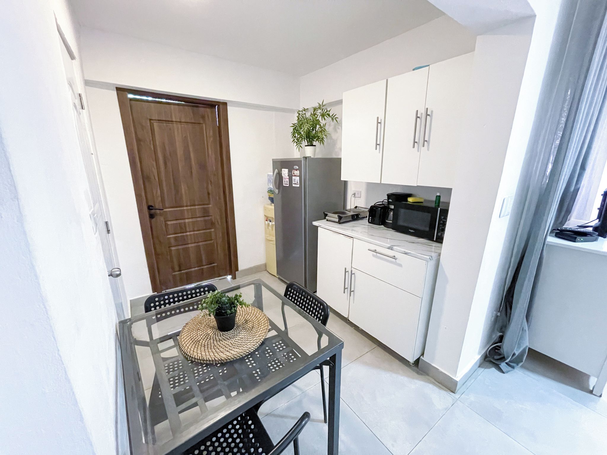 A compact kitchen with a refrigerator, microwave, and cabinets.