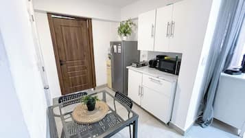 A compact kitchen with a refrigerator, microwave, and cabinets.