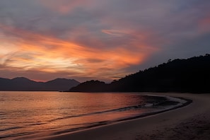 Una playa con mar tranquilo y cielo al atardecer.
