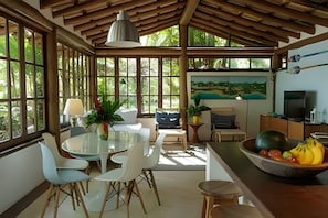 Amplia habitación con comedor, sofá, un cuadro y una encimera de cocina con fruta.