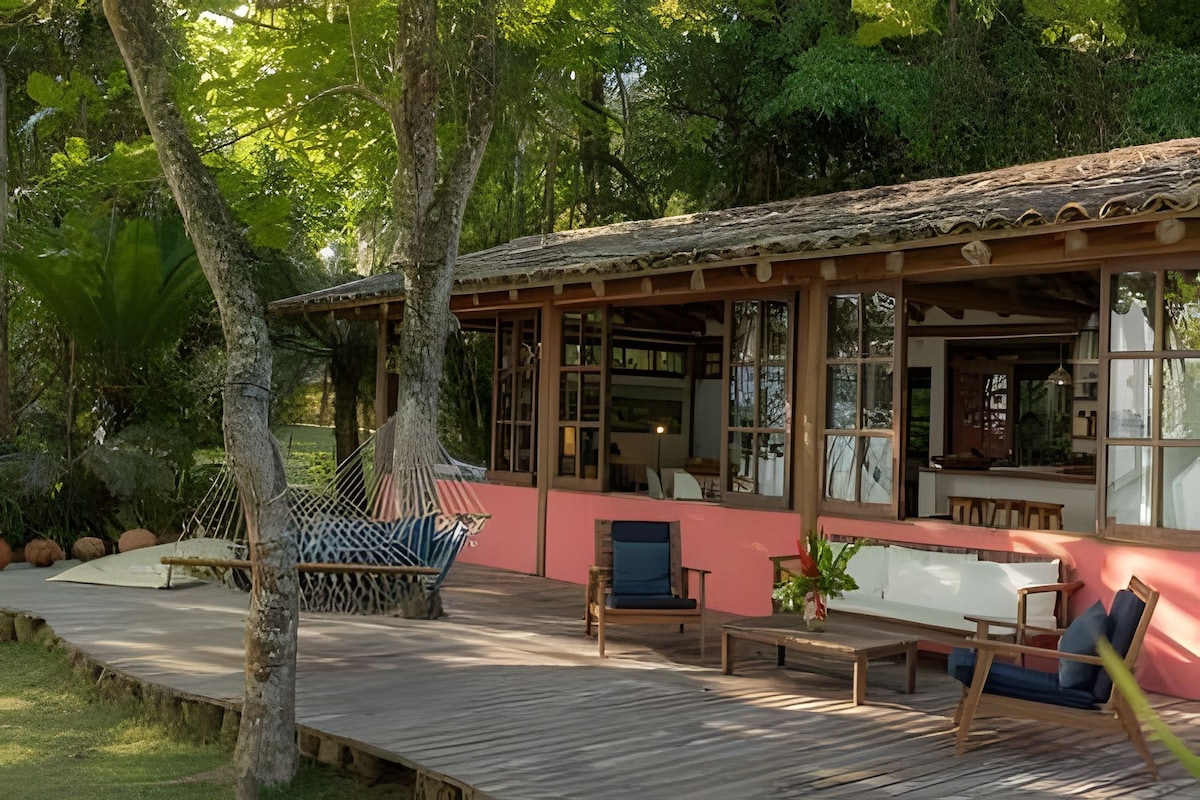 Una terraza de madera con una hamaca, una silla y una mesa.