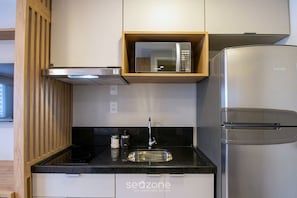 Eine moderne Küche mit einem Edelstahl-Kühlschrank, einer eingebauten Mikrowelle und einem Gasherd.