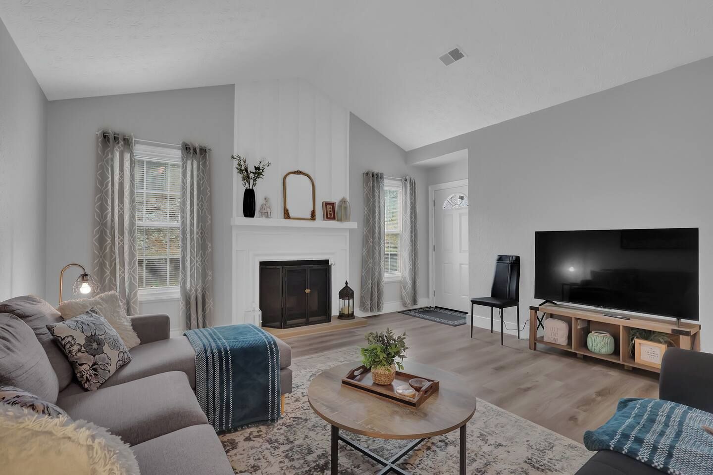 A modern living room with a fireplace, a flat-screen TV, and a sofa.