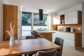 A modern kitchen with a wooden island, white cabinets, and a view of greenery outside. - Apartment Dalgona Delux (Podcetrtek)