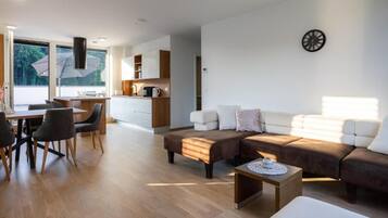 A modern living room with a sofa, coffee table, and dining area.