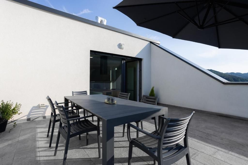 Une terrasse sur le toit, avec une table et des chaises, un pot de fleurs et un grand parasol.
