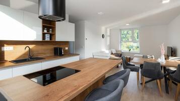Una cocina moderna con una isla de madera, electrodomésticos integrados y una zona de comedor con mesa y sillas.