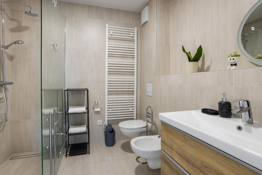 Un baño moderno con cabina de ducha de vidrio, inodoro blanco, bidé y tocador con espejo.