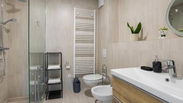 Un baño moderno con cabina de ducha de vidrio, inodoro blanco, bidé y tocador con espejo.