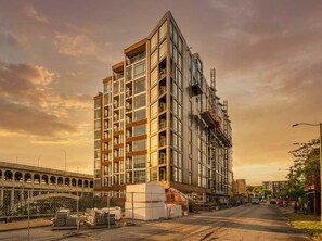 A multi-story building under construction with a modern architectural design, featuring a prominent central tower and a series of balconies. - Prime Cleveland Location  Modern 2BR + Balcony (Cleveland)