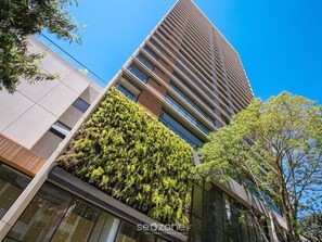 A modern high-rise building with a glass facade, a rooftop garden, and a clear blue sky. - Studio in Condo. w/ Pool and City View Gpe0011 (São Paulo)