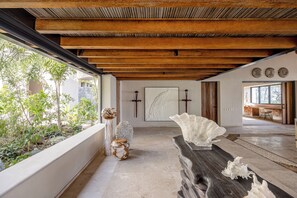 A modern interior with a wooden ceiling, a stone wall with a painting, and a large white sculpture. - Skypool. Luxury mansion with staff, chef and waiter included. (Ixtapa Zihuatanejo)