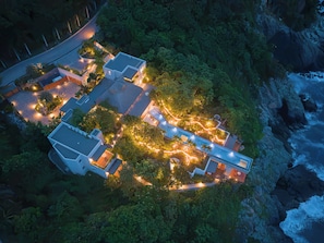 An aerial view of a coastal property with multiple buildings, a paved driveway, and surrounding greenery. - Skypool. Luxury mansion with staff, chef and waiter included. (Ixtapa Zihuatanejo)