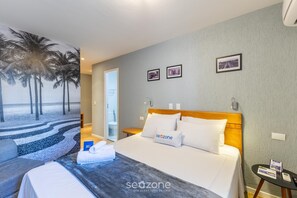 A hotel room with a bed, a nightstand, a wall-mounted lamp, and a door leading to a bathroom. - Well-located Apt. w/ City View Rhn0047 (Curitiba)