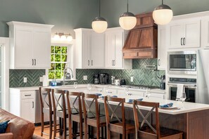 Una cocina moderna con armarios blancos, salpicadero tipo espiga y una isla central con taburetes de bar.
