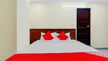 A hotel room with a bed, a wooden headboard, a red and white bedspread, and a door.