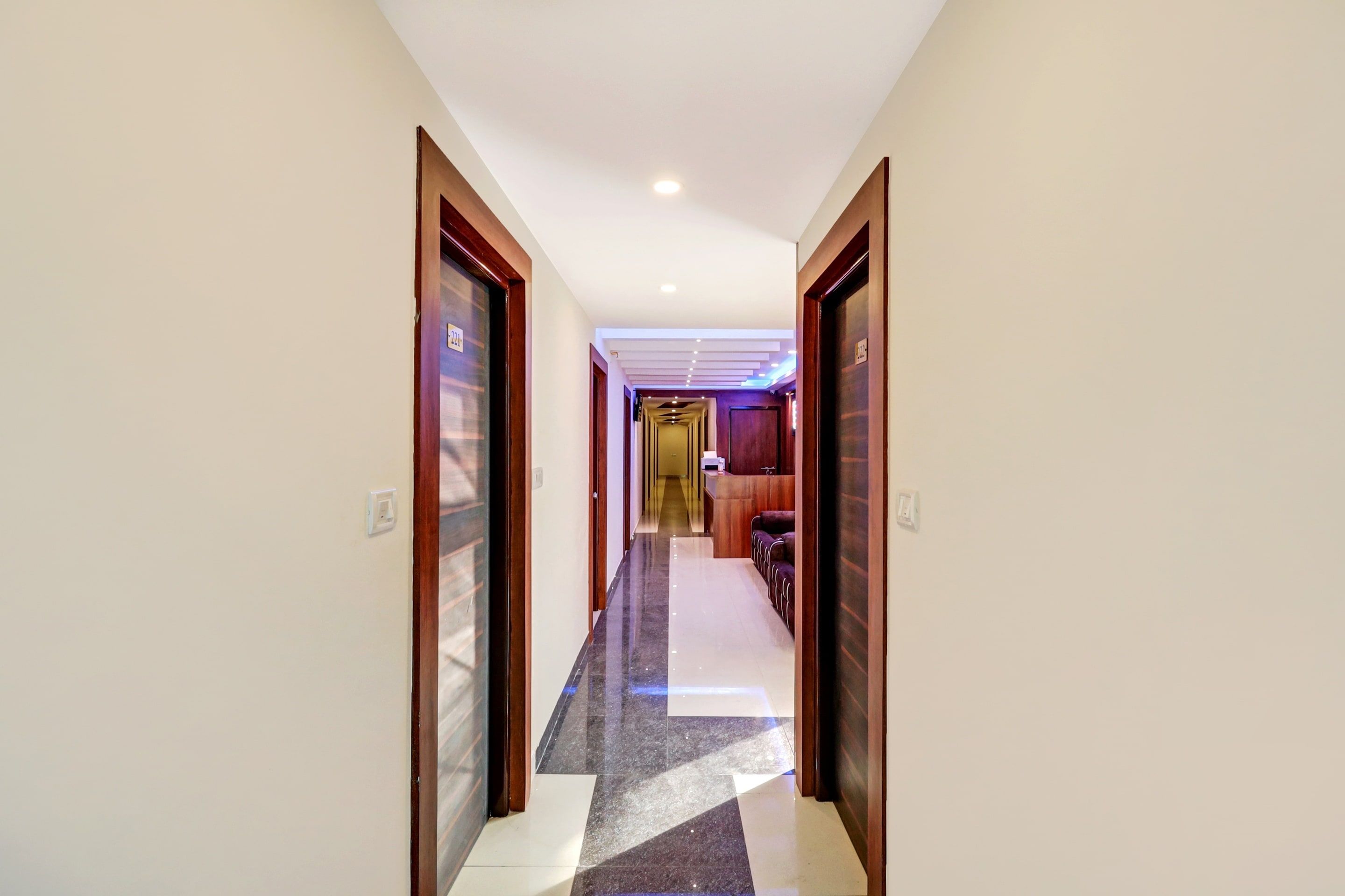 A hotel hallway with a check-in desk, a reception area, and a seating area.