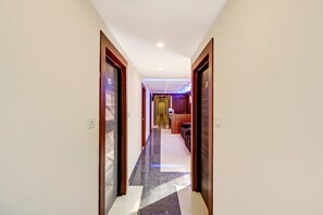 Um corredor de hotel com balcão de check-in, área de recepção e espaço para sentar.