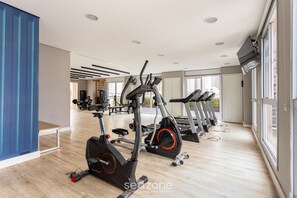 A gym with multiple treadmills, exercise bikes, and a wooden floor. - Studio Well Located w/ Terrace Mop0605 (São Paulo)
