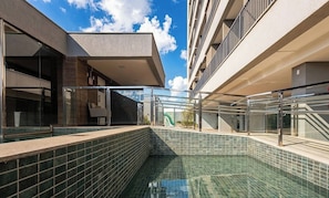 A modern outdoor swimming pool with a glass barrier, surrounded by buildings with balconies. - Apt. in Condo. w/ Pool and City View Grlb0801 (Anapolis)