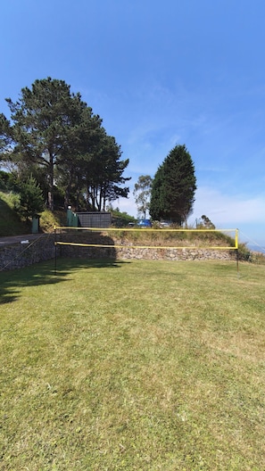 A grassy area with a stone wall and a yellow netted structure, possibly for sports. - Country house between the sea and the mountains—pets welcome!—with direct access to the beach (Caravia)