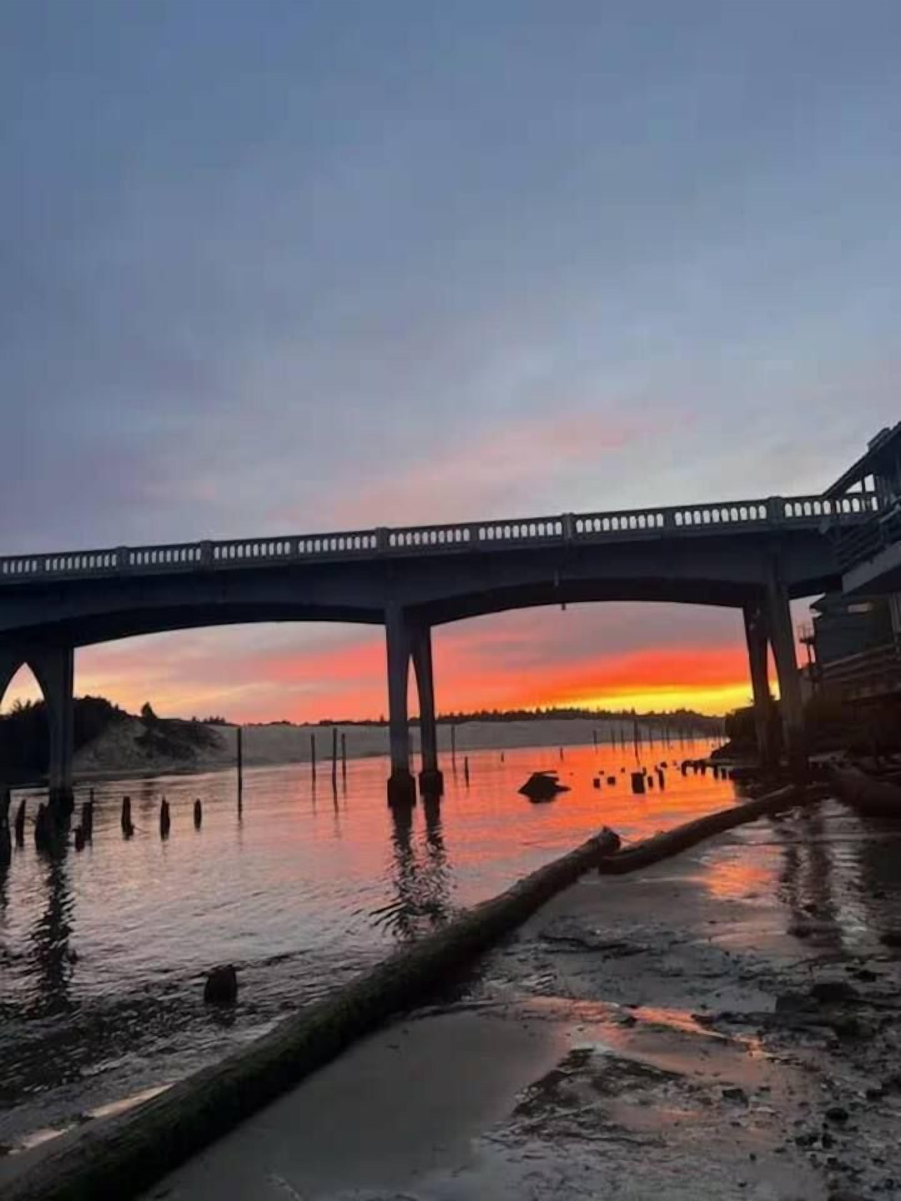 Uma ponte sobre a água, com o pôr do sol ao fundo.
