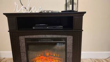 A fireplace with a TV on top, a decorative sign above it, and a remote control on the mantel.