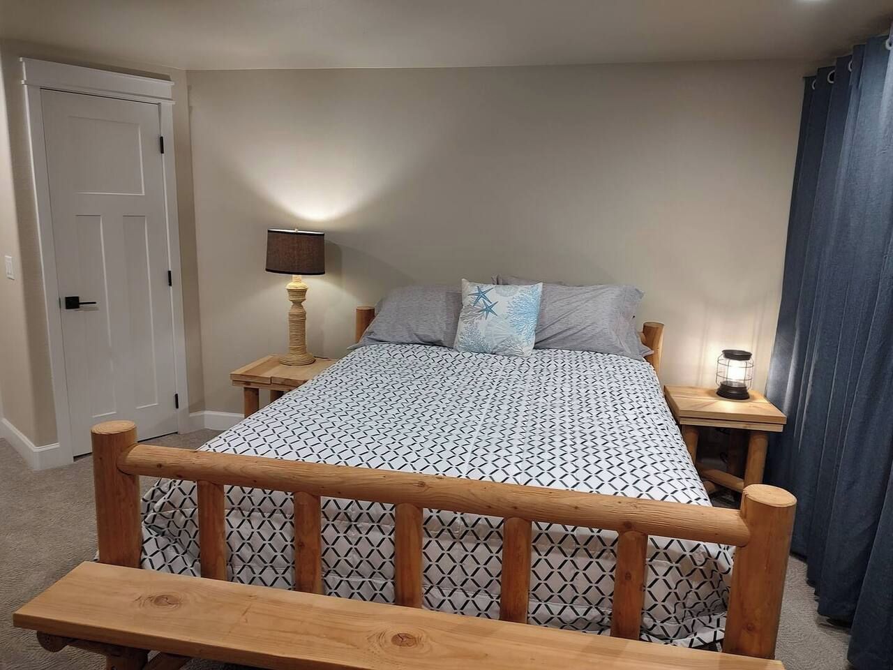 A bedroom with a wooden bed frame, a bedside table with a lamp, and a bench at the foot of the bed.