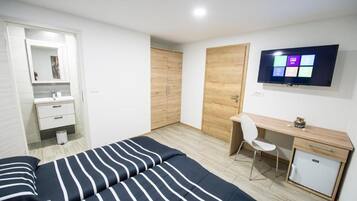 Un dormitorio con cama, escritorio, silla, televisor y armario.