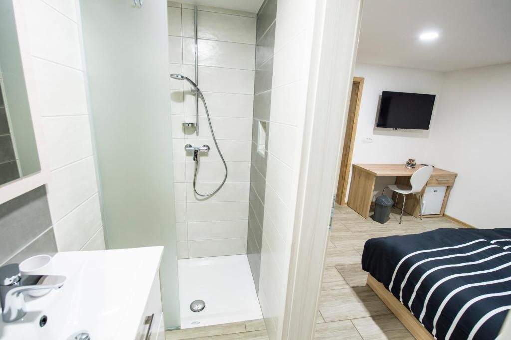 Une chambre d’hôtel équipée d’une douche, d’un bureau, d’un lit et d’une télévision.