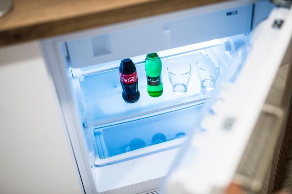A refrigerator with two bottles and two glasses inside.