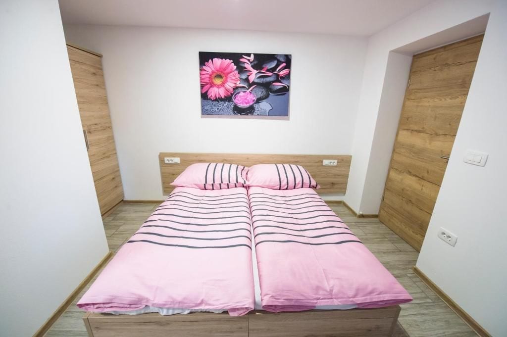 Un dormitorio con cama doble, cabecera de madera y un cuadro de flores en la pared.