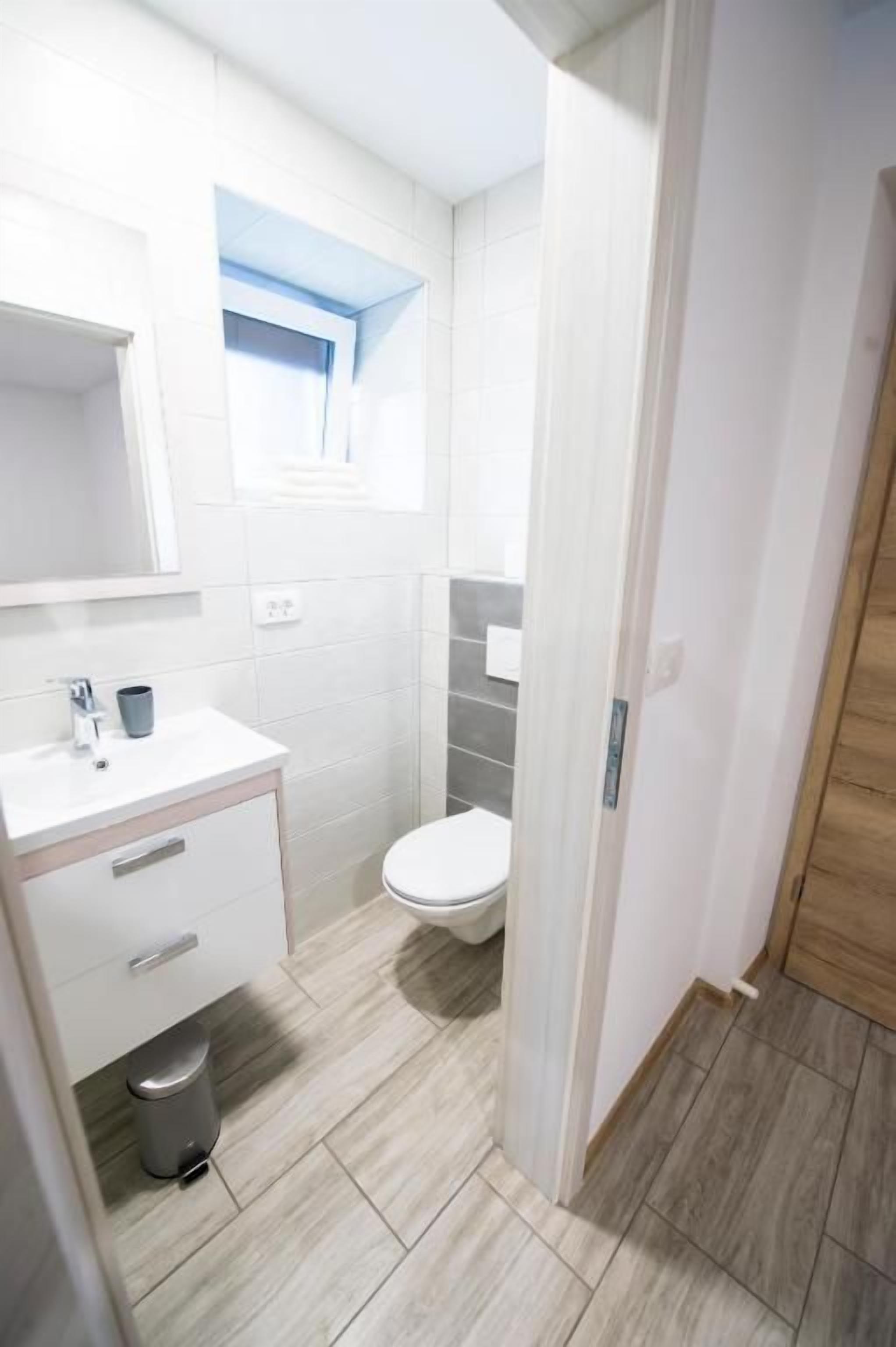 A bathroom with a white sink, mirror, and toilet.