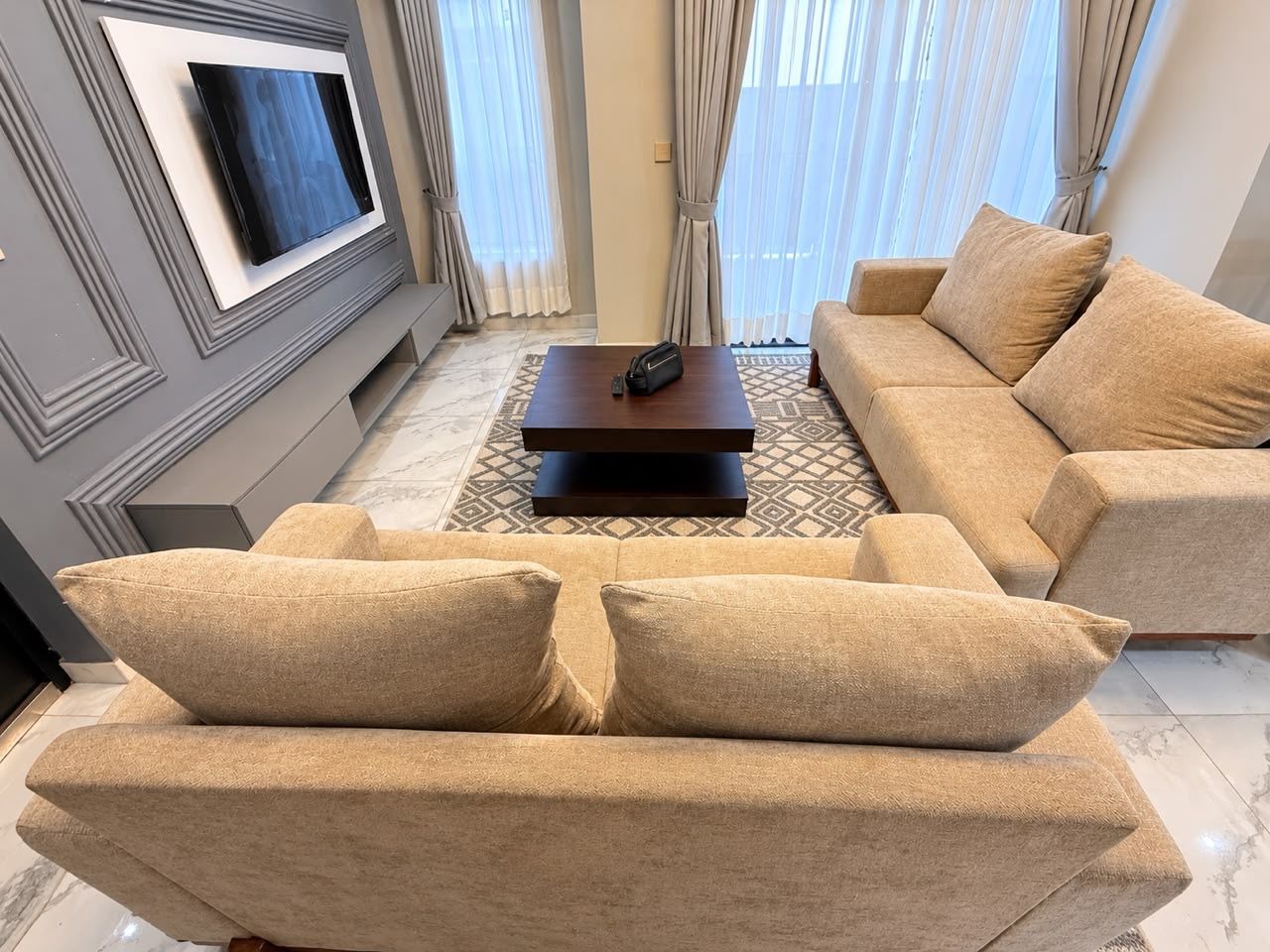 Un salon comprenant un canapé, une table basse et un téléviseur à écran plat fixé au mur.