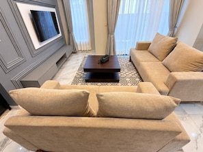 Un salon comprenant un canapé, une table basse et un téléviseur à écran plat fixé au mur.