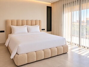 Une chambre moderne avec un grand lit, une tête de lit et une fenêtre avec des rideaux.